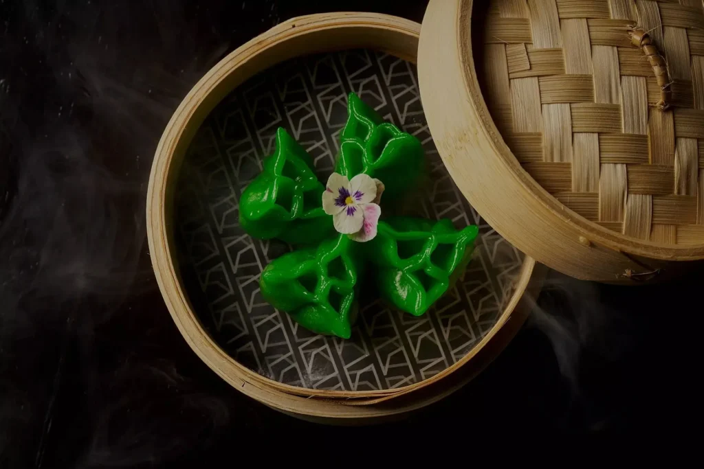 Dumplings verdes al vapor en canasta de bambú con flor comestible